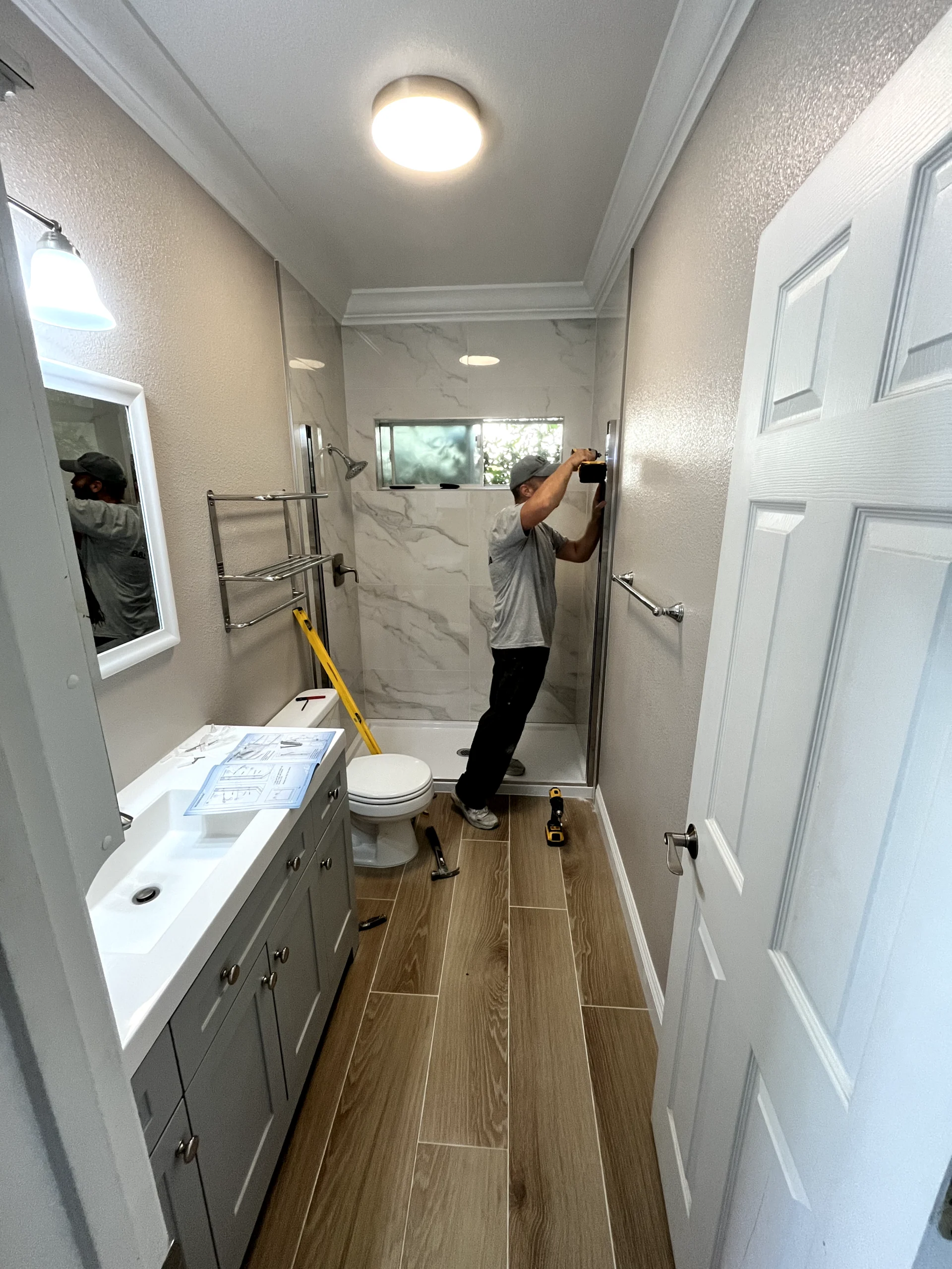Bathroom remodel installation in Sacramento with new shower walls, vanity, flooring, and fixture updates in progress.