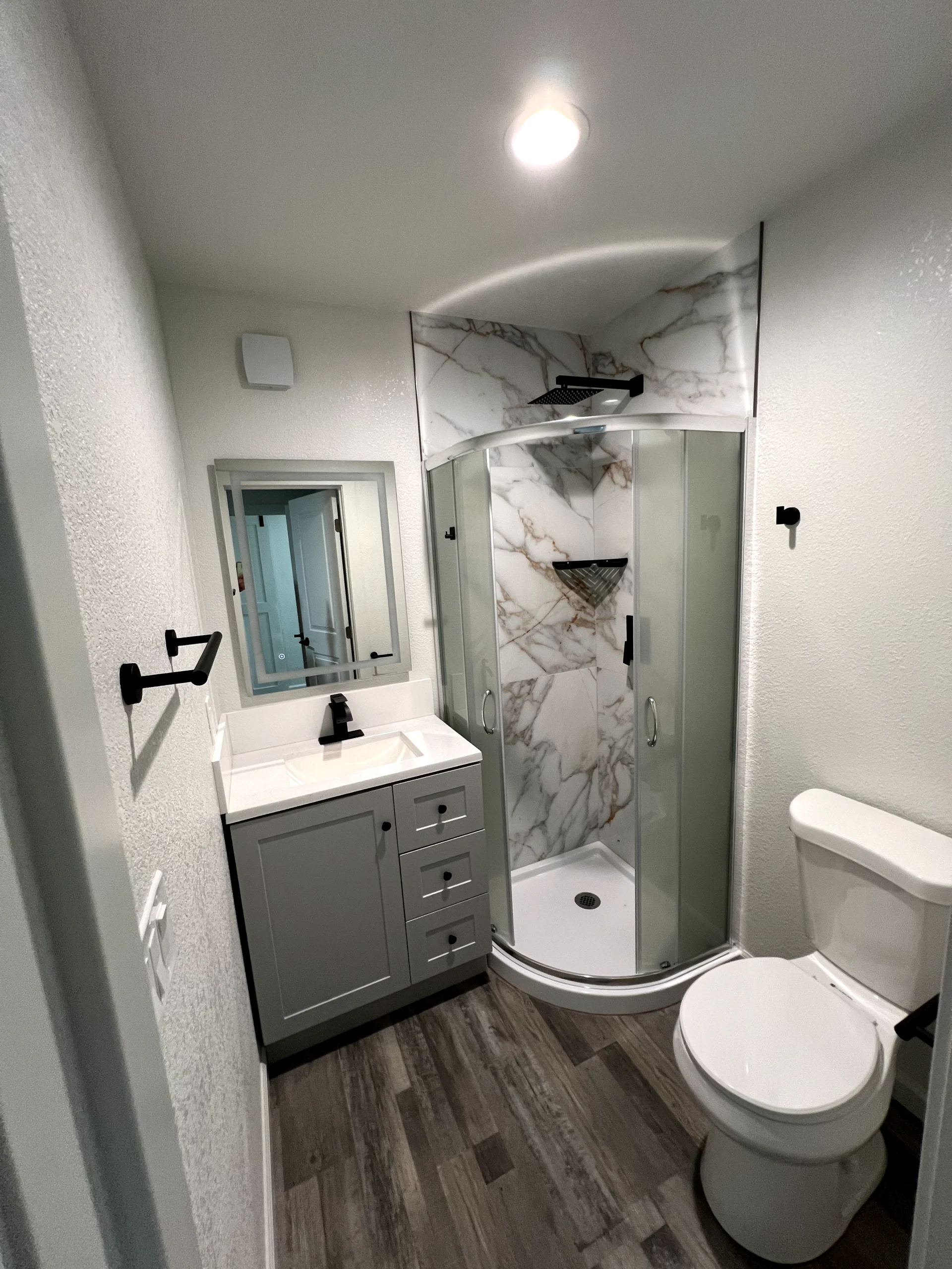 Glass shower enclosure installation in Roseville with marble-look shower panels, black hardware, and clean white shower base.