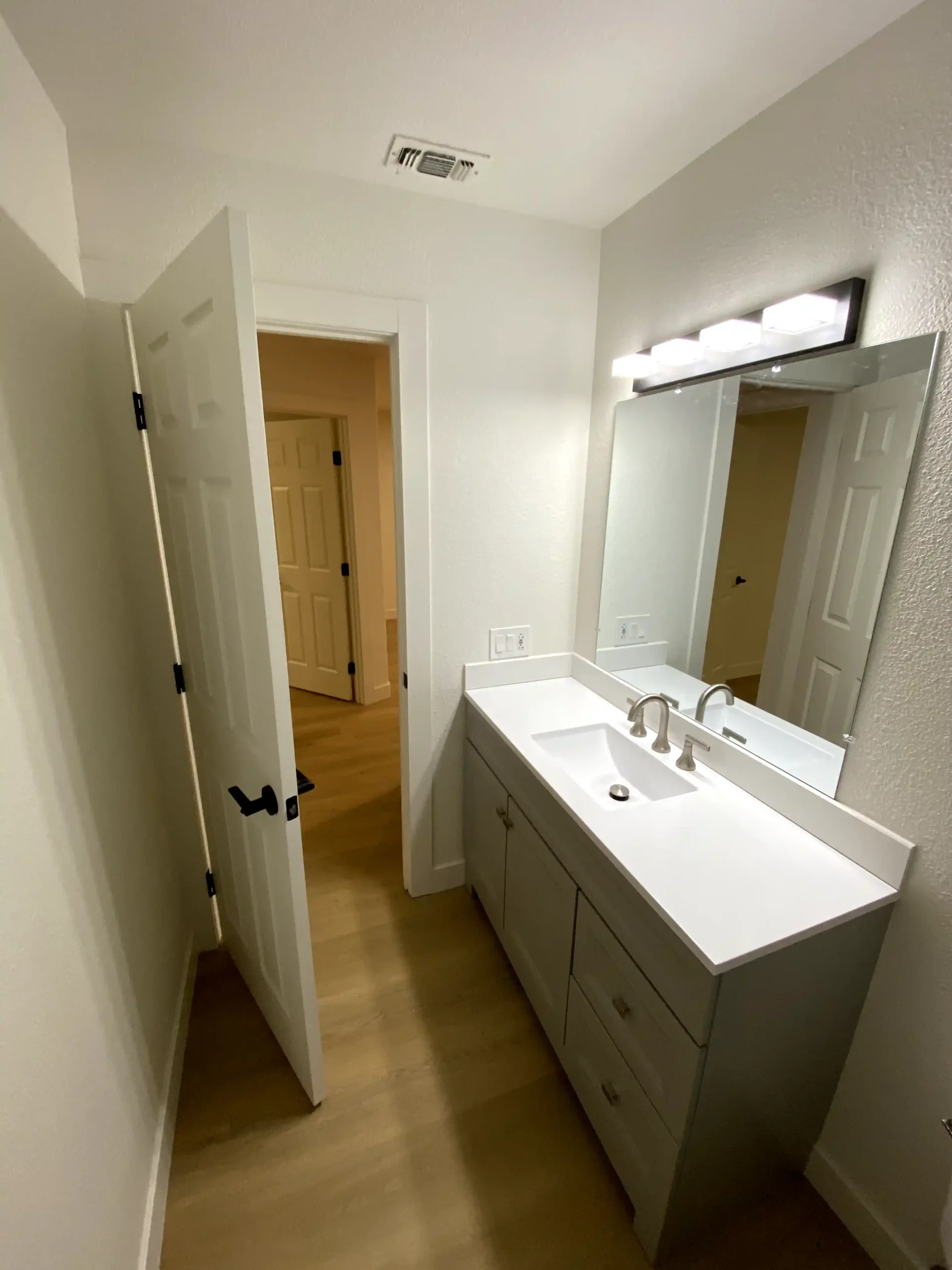 Guest bathroom vanity remodel in Rocklin with gray cabinet, white countertop, updated faucet, modern mirror, and clean wall lighting.
