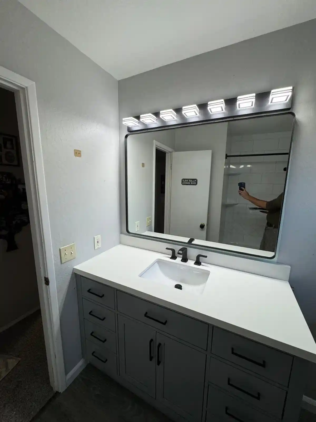 Bathroom vanity and shower remodel in Granite Bay with gray cabinet, black fixtures, modern mirror, and updated shower wall panels.