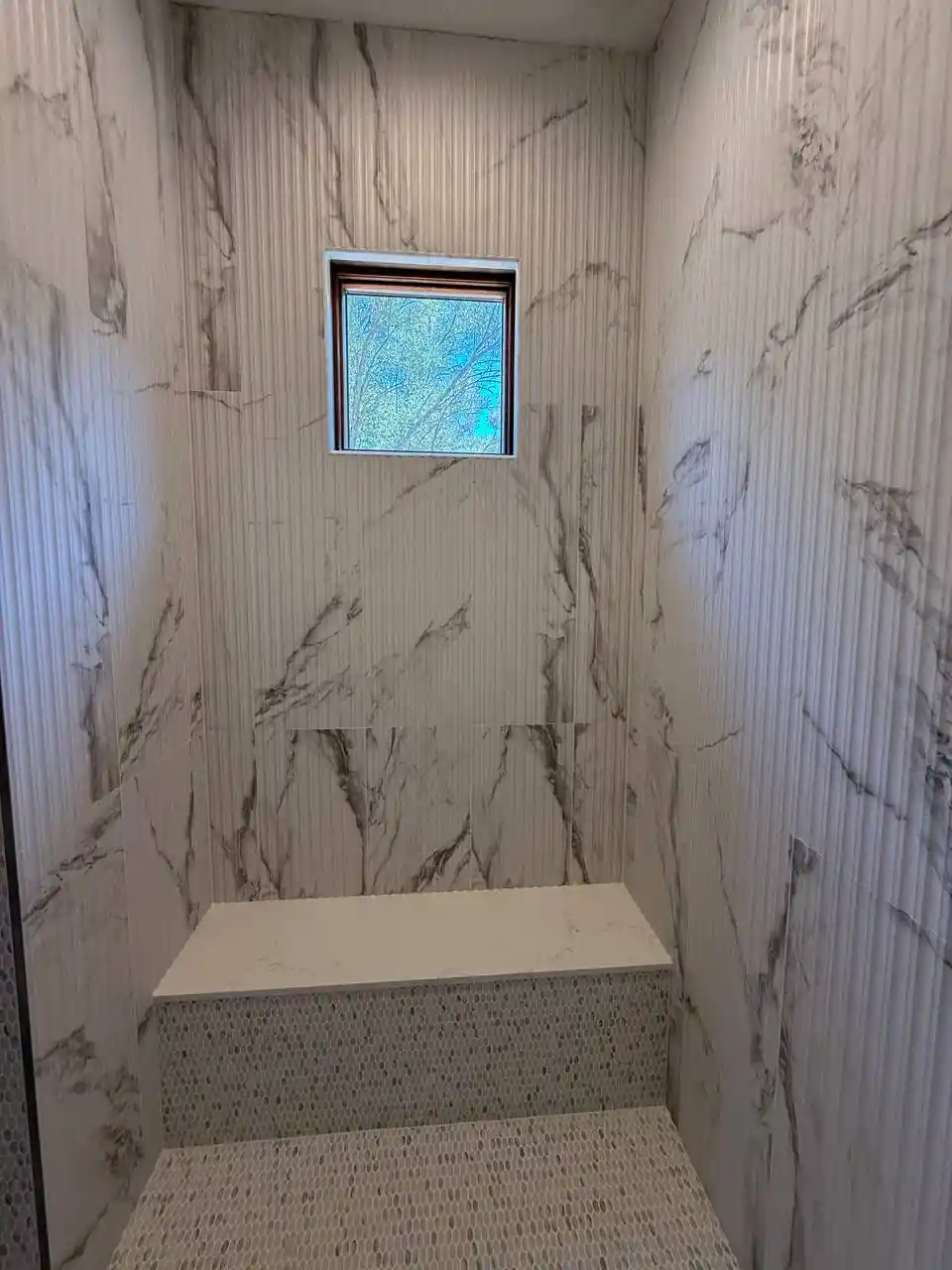 Glass shower enclosure installation in Roseville with marble-look shower panels, black hardware, and clean white shower base.