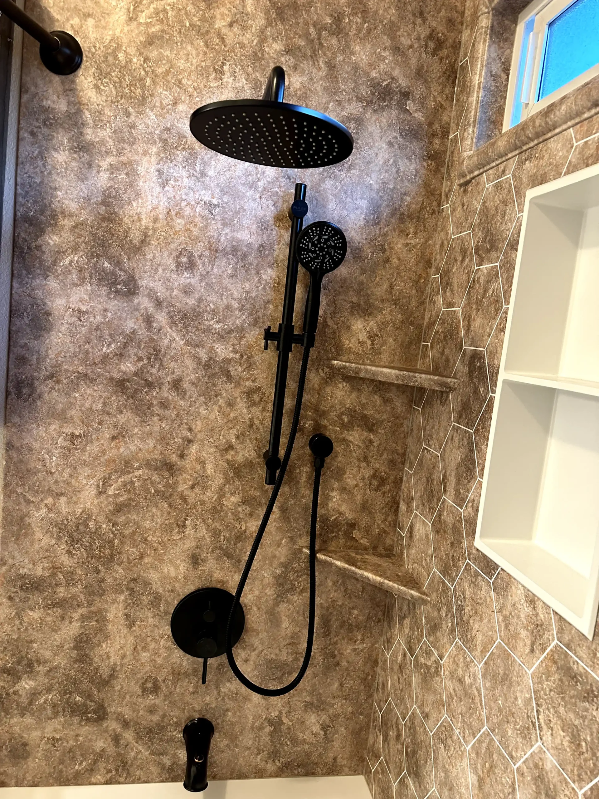 Custom shower tile installation in Sacramento with white scallop tile, blue accent tile, shower niche, bathtub, and brass shower fixtures.