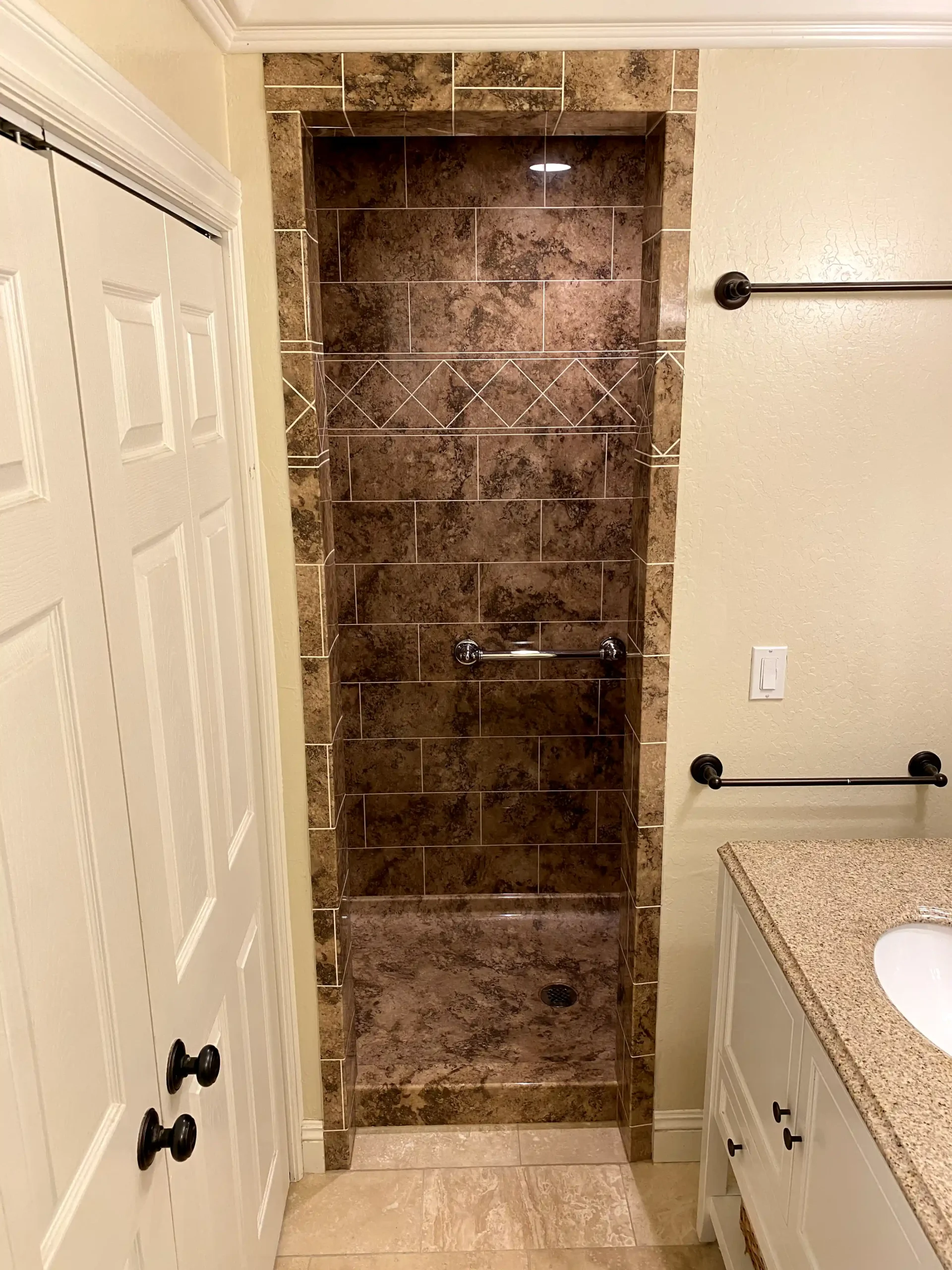 Glass shower enclosure installation in Roseville with marble-look shower panels, black hardware, and clean white shower base.