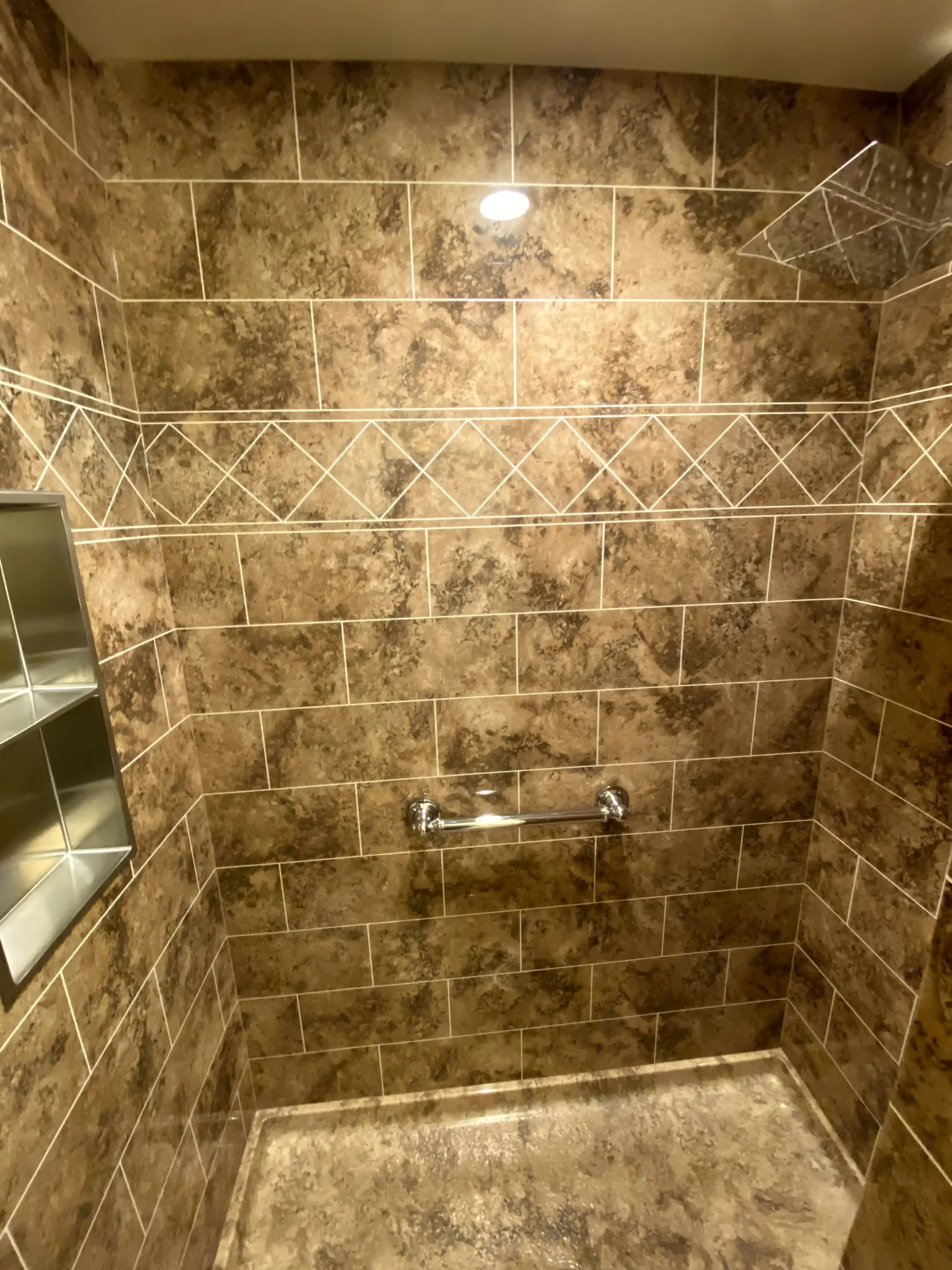 Walk-in shower remodel in Elk Grove with marble-look wall tile, sliding glass door, rainfall shower head, and built-in storage.
