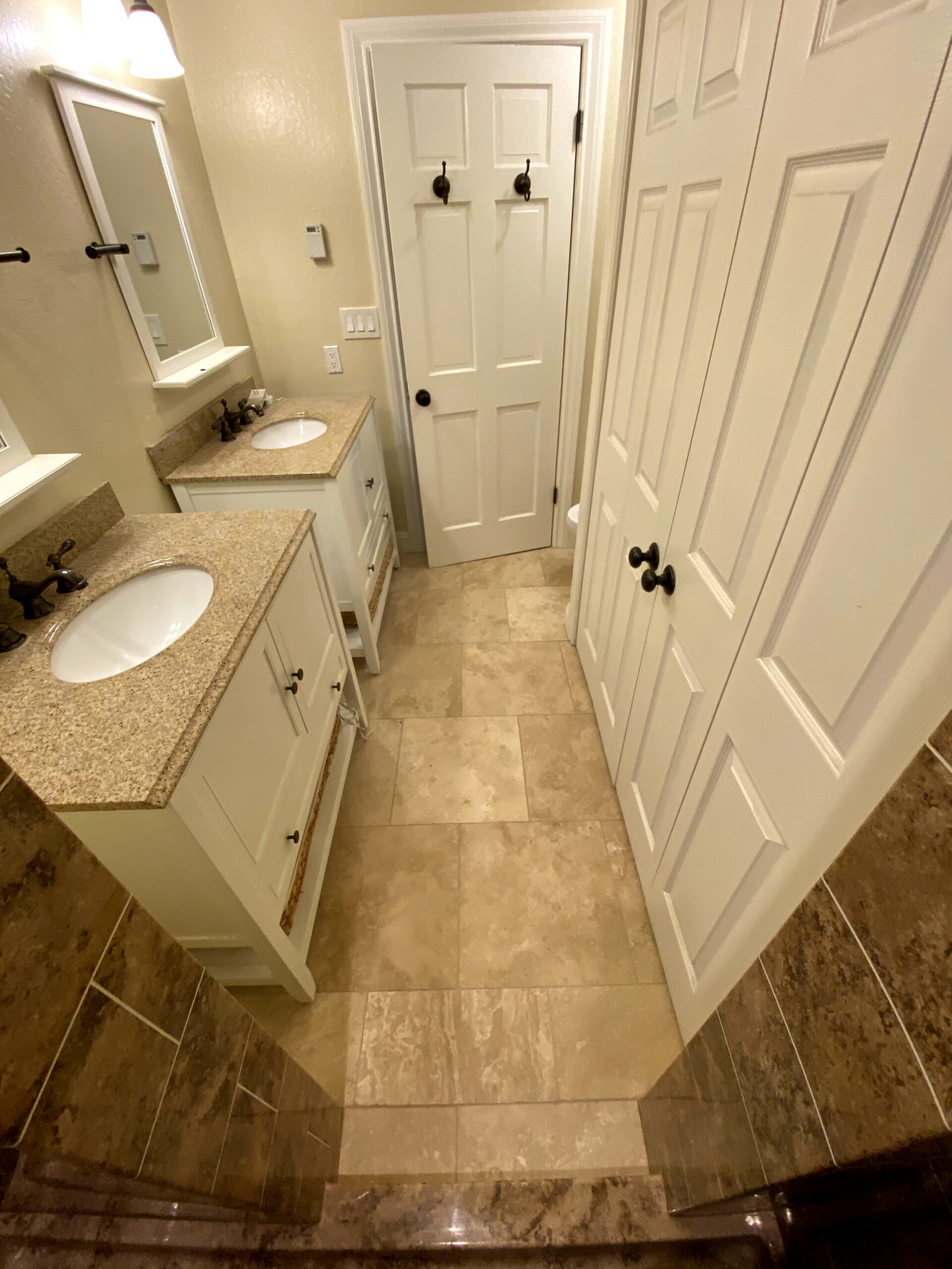 Walk-in shower remodel in Elk Grove with marble-look wall tile, sliding glass door, rainfall shower head, and built-in storage.