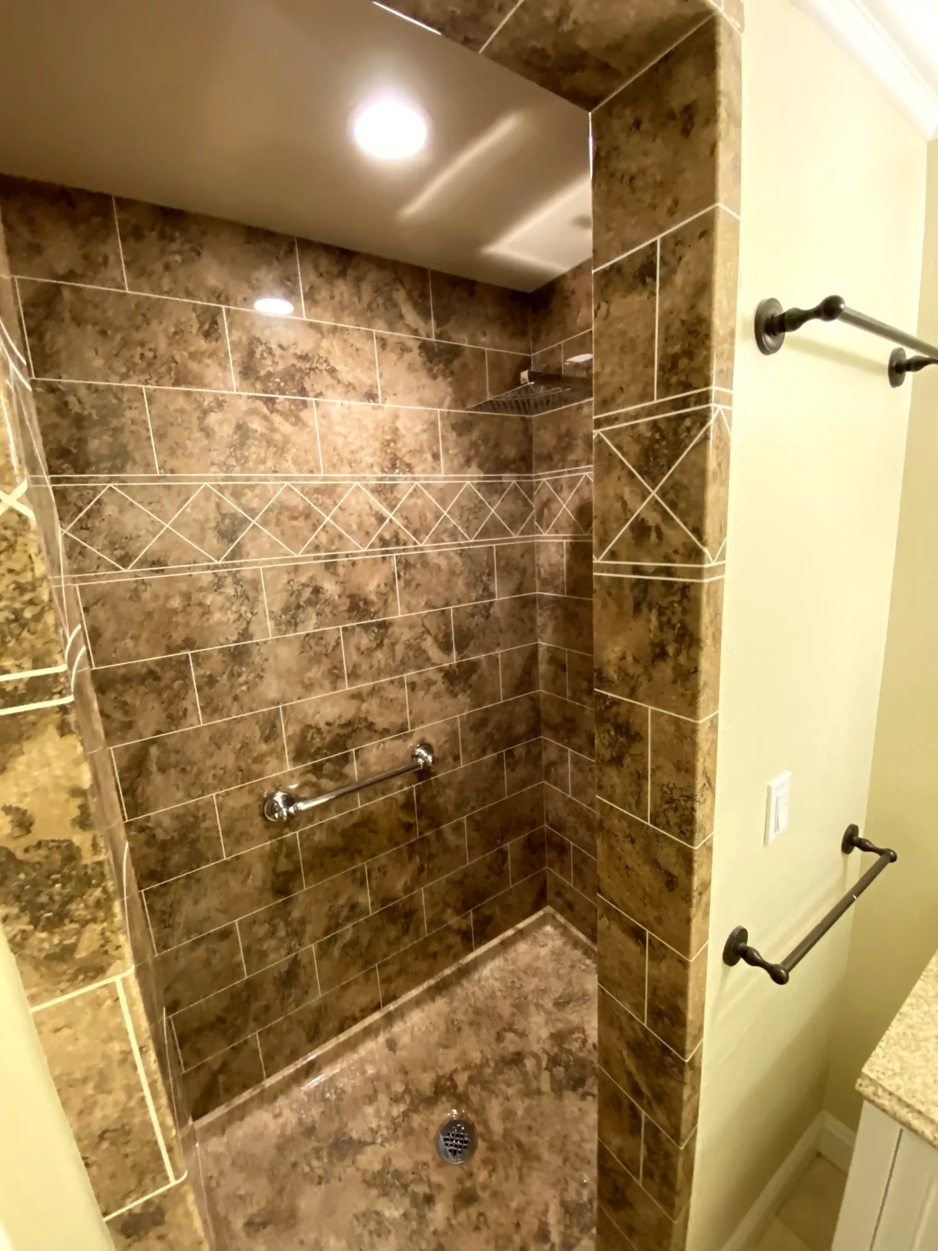Walk-in shower remodel in Elk Grove with marble-look wall tile, sliding glass door, rainfall shower head, and built-in storage.