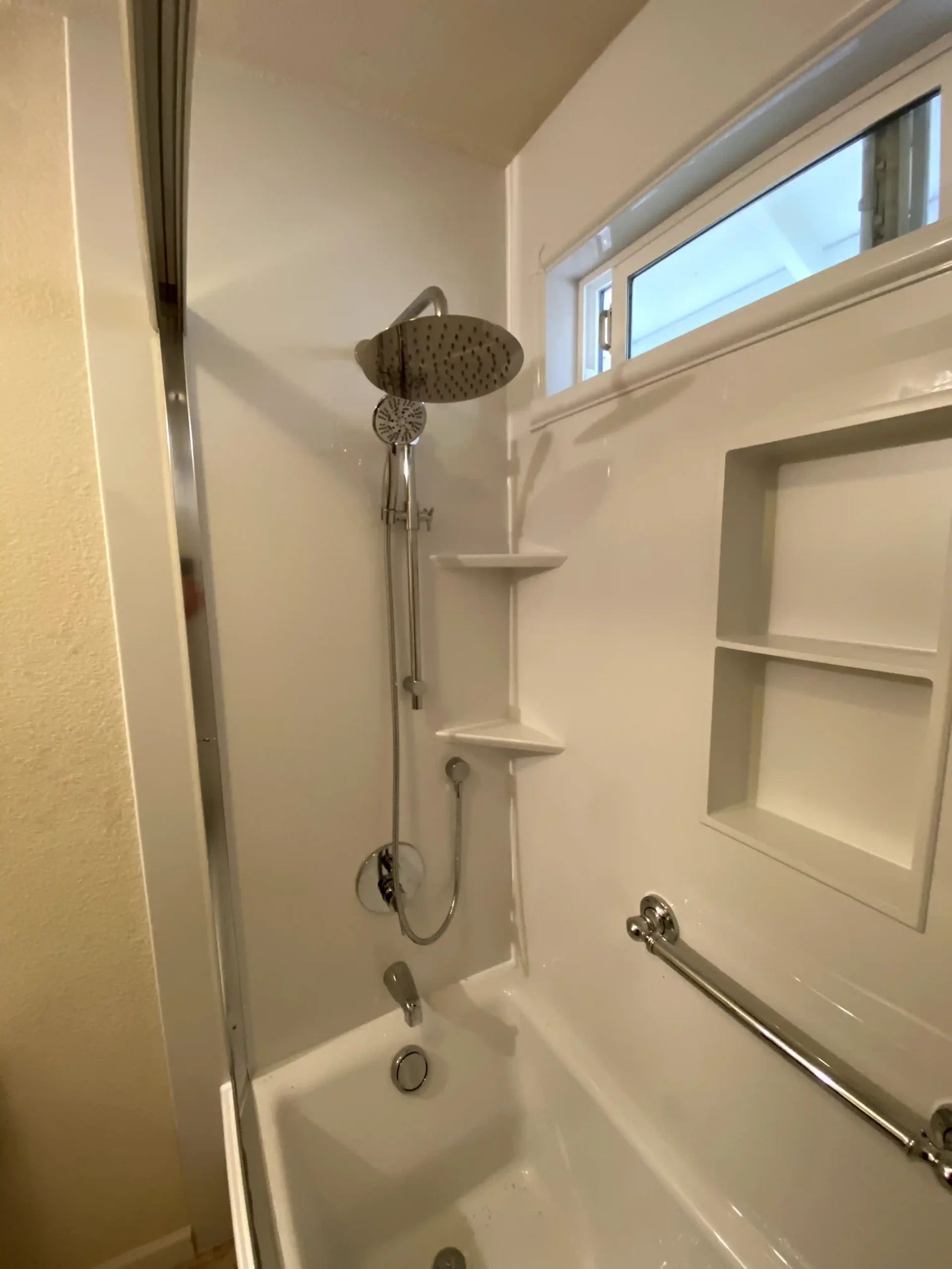 Bright guest bathroom remodel in Fair Oaks with white vanity, brass hardware, marble-look flooring, arched tub area, and blue accent tile.