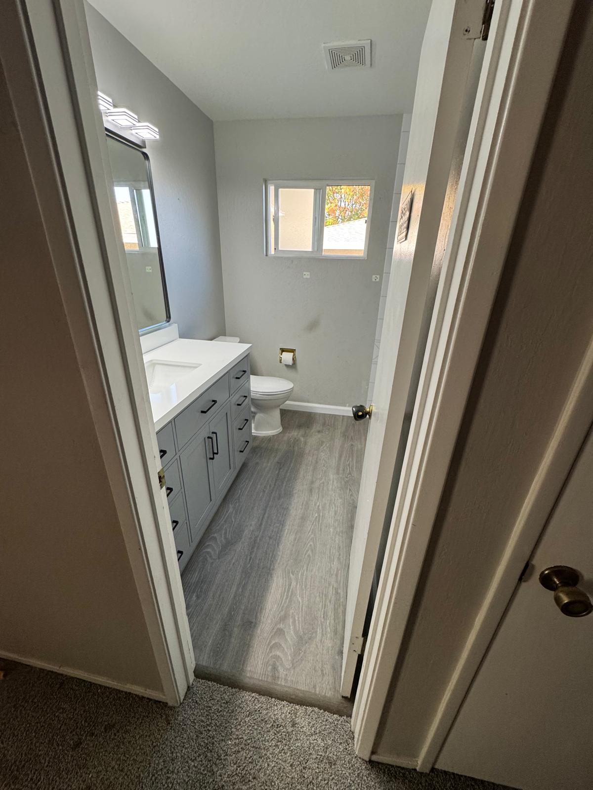 Bathroom remodel installation in Sacramento with new shower walls, vanity, flooring, and fixture updates in progress.